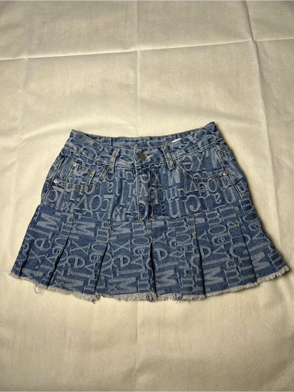 Y2K style denim mini skirt with repeating white text pattern